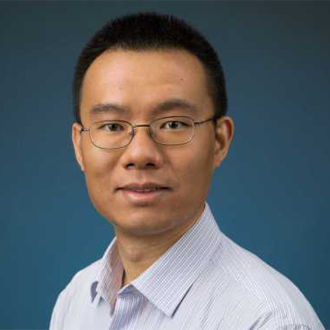 Dr. Xinhua Zhang smiles at camera in glasses